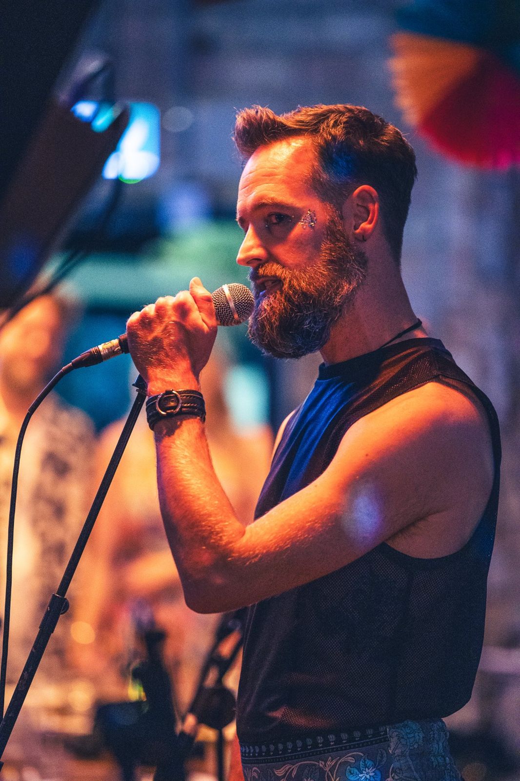 Dan performing into a handheld microphone under warm stage light